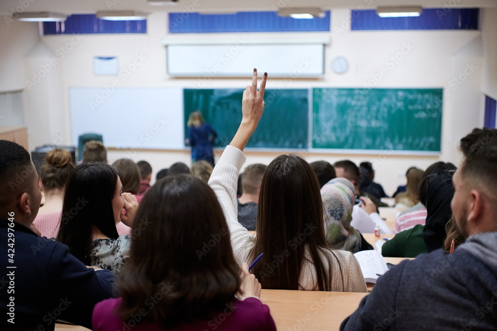 female student sitting in the class and raising hand up