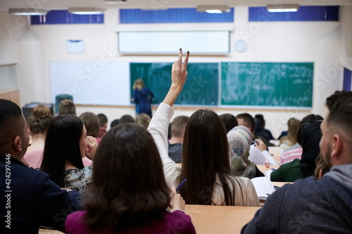 Fotografia female student sitting in the class and raising hand up
