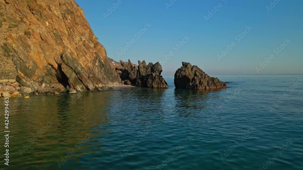 Drone getting near two rocks at the sea during sunset Drone getting near two rocks at the sea during sunset