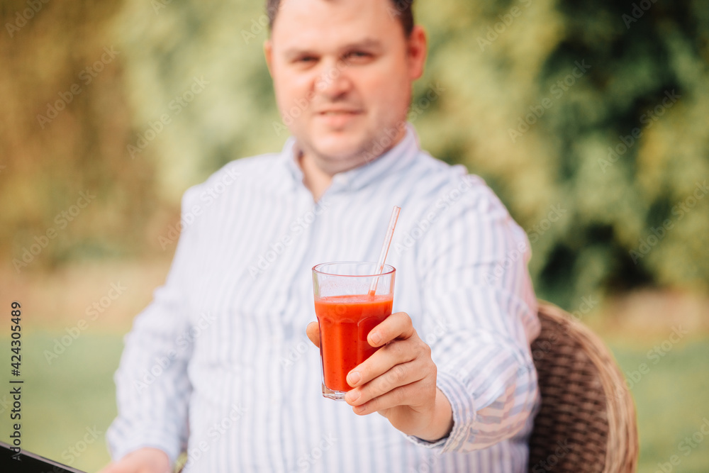 Man drinks a smoothie with a glass drinking straw. To eat healthy food. Plastic-free and eco-friendly. Red juice in a glass Man drinks a smoothie with a glass drinking straw. To eat healthy food. Plastic-free and eco-friendly. Red juice in a glass