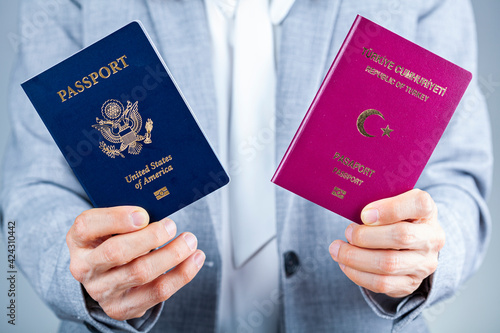 A woman in formal clothes is holding Turkish and US passports. Concept image for immigration to USA, path to citizenship, dual citizen, living abroad and application process for being a US citizen.