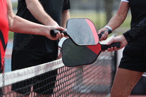 A pickleball match ends with players bumping paddles. photo