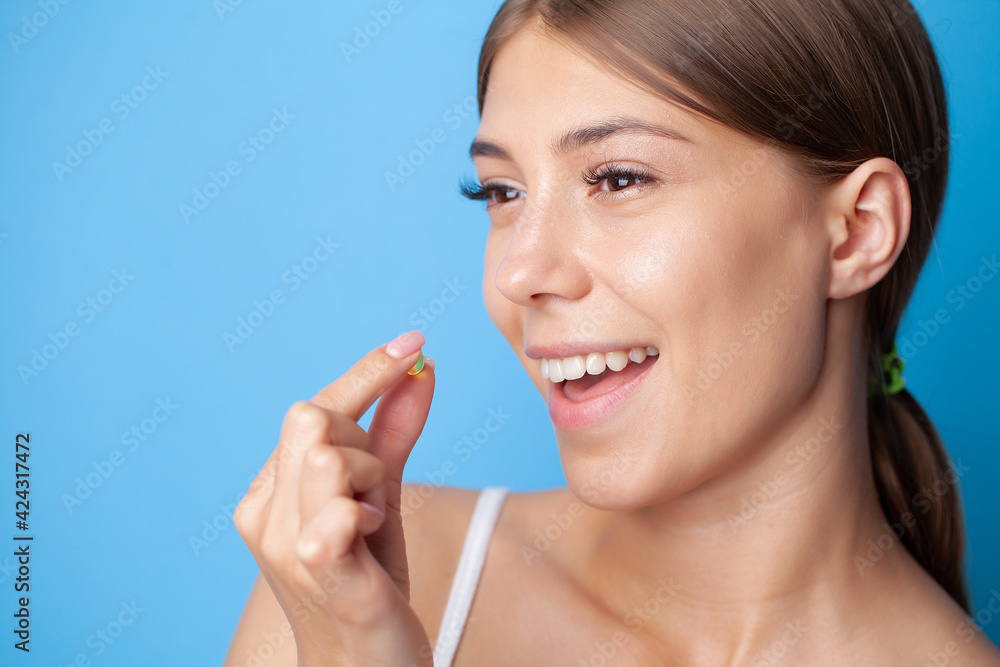 Portrait of smiling young woman with Omega 3 fish oil capsule Portrait of smiling young woman with Omega 3 fish oil capsule