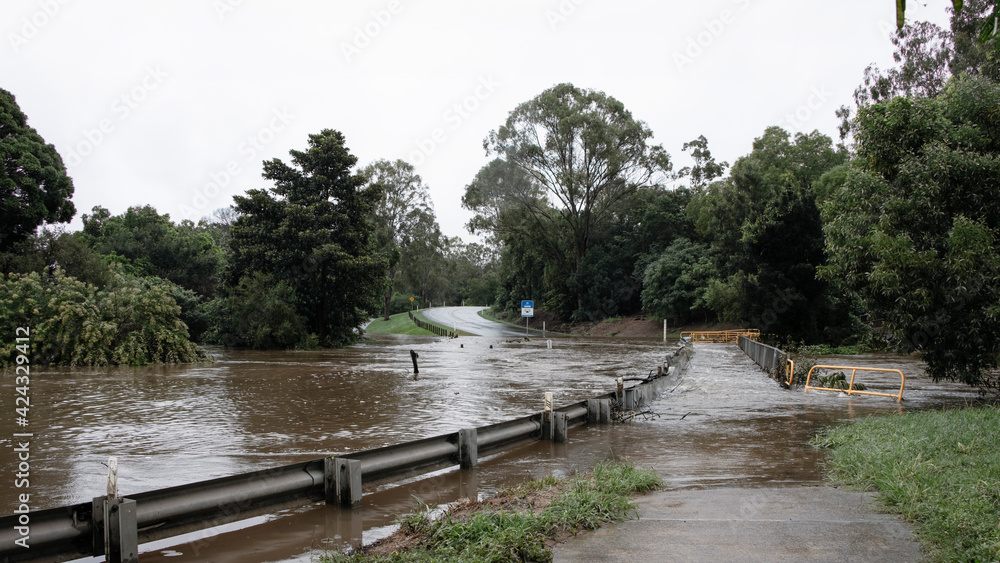 Queensland Australia 23 March 2021 Flooded Road after torrential rain and dam overflowing. River overflowing onto Youngs Crossing and over the pedestrian walkway.