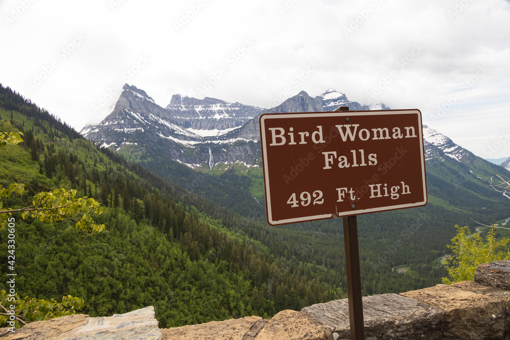 Bird Woman Falls sign and waterfall in background, Glacier National Park, Montana Bird Woman Falls sign and waterfall in background, Glacier National Park, Montana