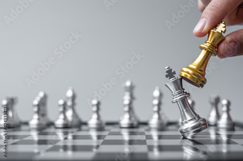 Fotografering businessman hand moving gold Chess King figure and Checkmate opponent during chessboard competition