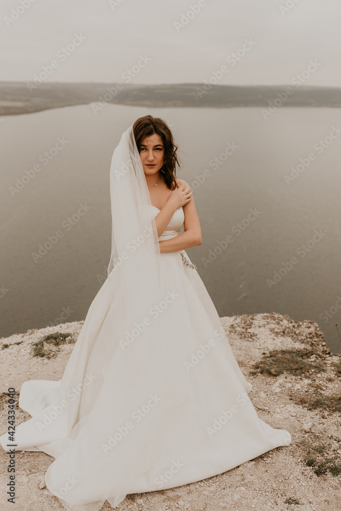 bride woman with short haircut in white wedding corset dress strapless and with a long chiffon veil on head