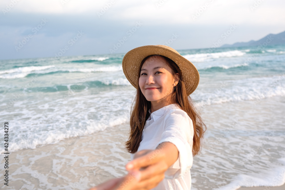 A beautiful young asian woman holding hand and leading her boyfriend to the beach for follow me concept A beautiful young asian woman holding hand and leading her boyfriend to the beach for follow me concept