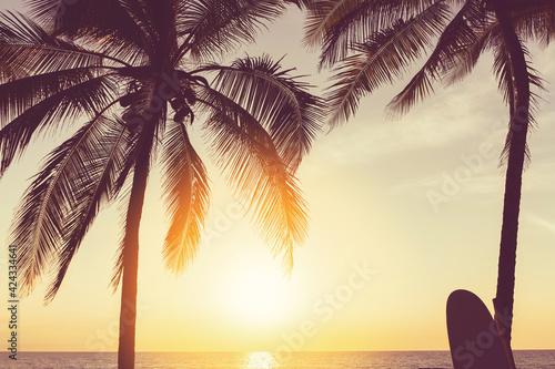 Deska surfingowa i palmy na tle plaży.
