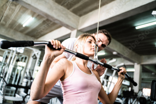 Smart sport women lift up barbell with trainer man in gym