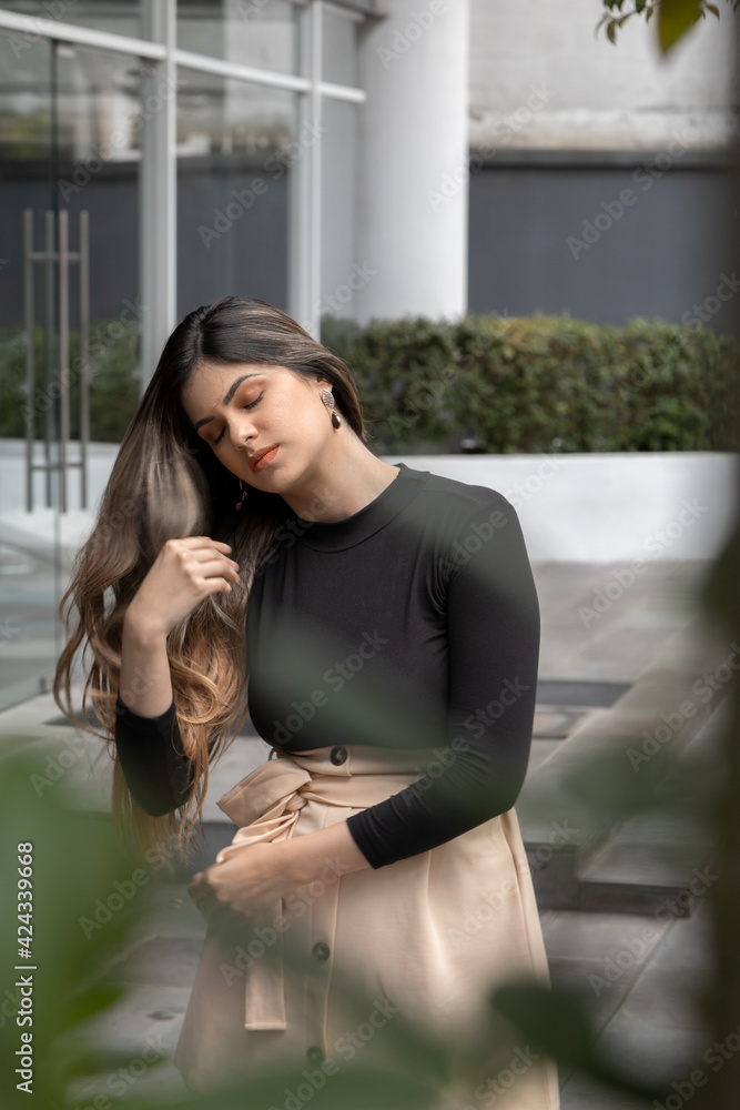 young, distracted latina woman sitting and relaxed has long blonde hair and fashionable clothes, model in the city