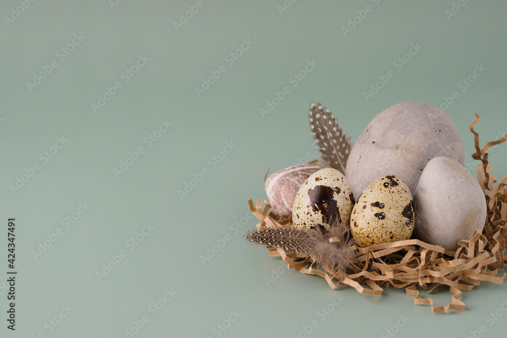 Quail eggs, round stones and feathers lie on a pastel blue background, close-up. Natural modern Easter background. Creative minimalistic Easter concept Quail eggs, round stones and feathers lie on a pastel blue background, close-up. Natural modern Easter background. Creative minimalistic Easter concept