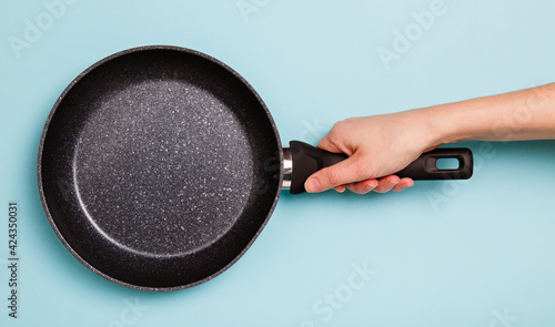 Obraz na plátne frying pan in woman's hand on blue background