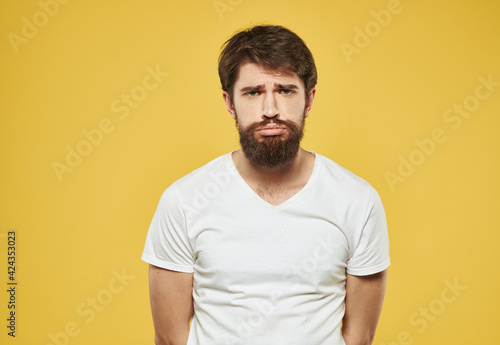 Portrait of a sad man on a yellow background cropped view of a white t-shirt