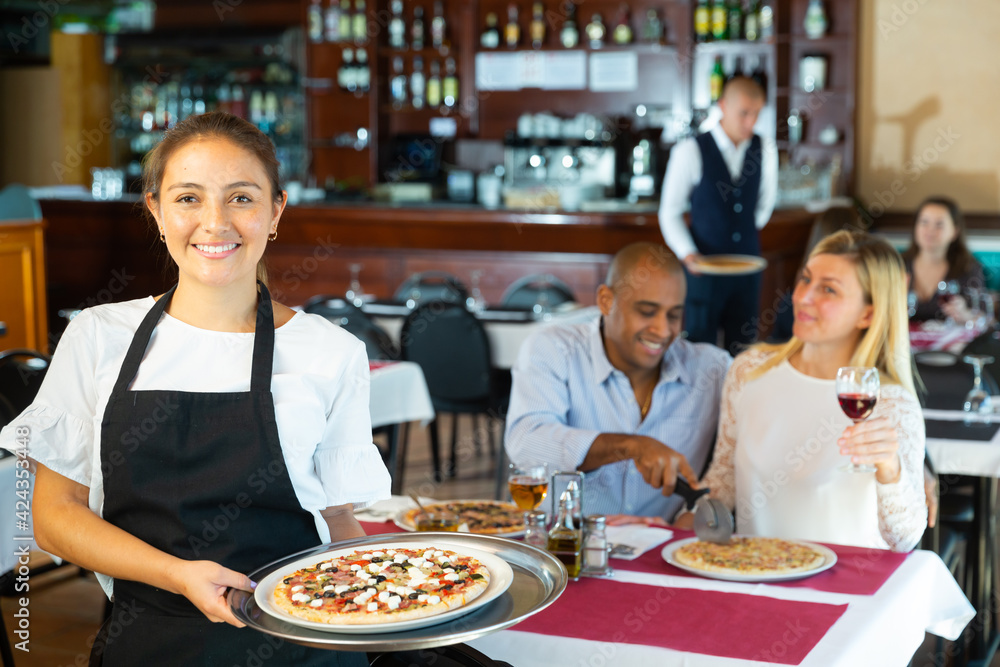 Portrait of waitress with serving tray pizza offering dishes in restaurant