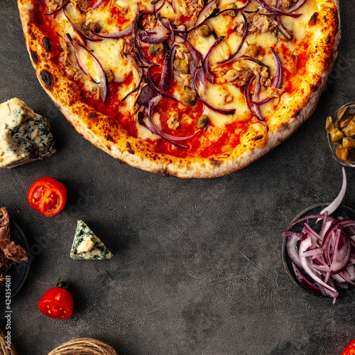 Fresh baked tuna and capers pizza on the decorated grey background