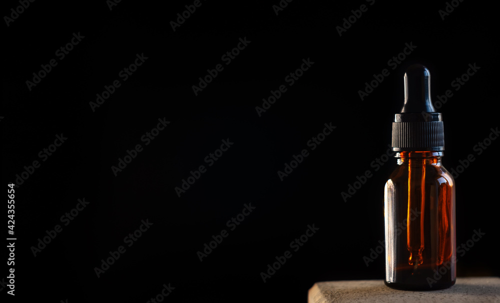 A glass dropper bottle with a pipette with a black rubber tip on a beautiful black background. The concept of nature skin. Organic Spa Cosmetics. A fashionable concept. The concept of a beauty salon A glass dropper bottle with a pipette with a black rubber tip on a beautiful black background. The concept of nature skin. Organic Spa Cosmetics. A fashionable concept. The concept of a beauty salon
