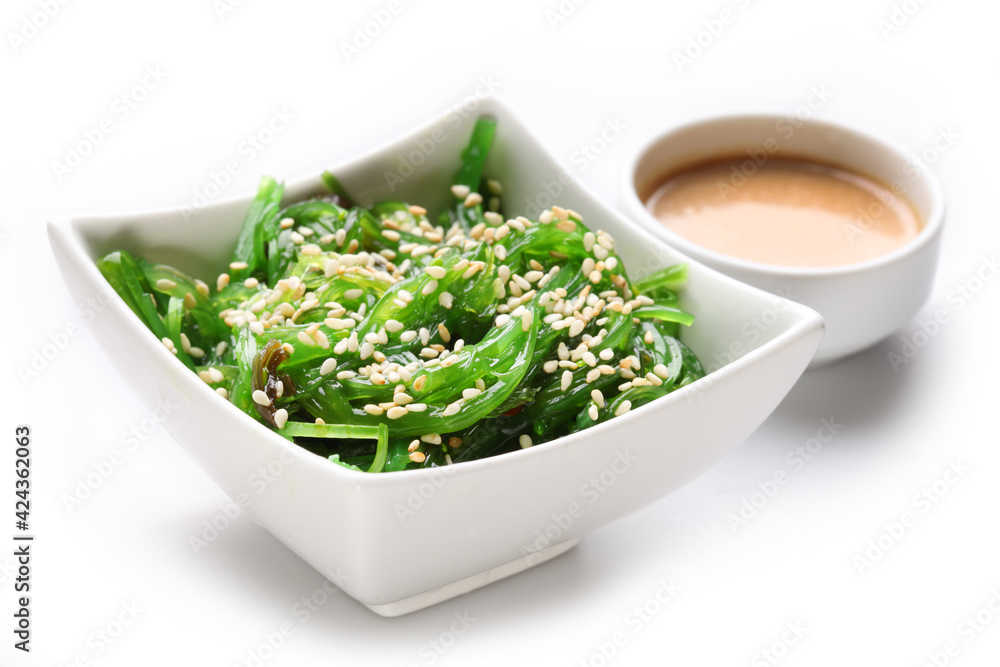 Japanese hiyashi wakame chuka salad with white sesame seeds and peanut sauce in a bowl on a white background. Japanese hiyashi wakame chuka salad with white sesame seeds and peanut sauce in a bowl on a white background.