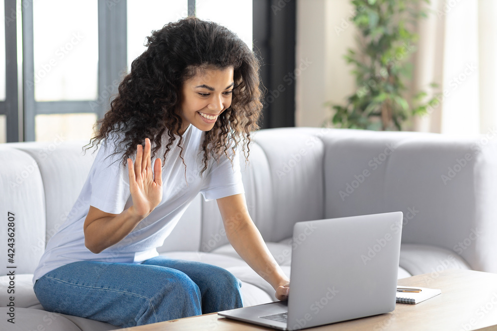 Smiling young African American woman wave hand at camera, talk on webcam, video call on computer. Happy female take online educational course or training Smiling young African American woman wave hand at camera, talk on webcam, video call on computer. Happy female take online educational course or training