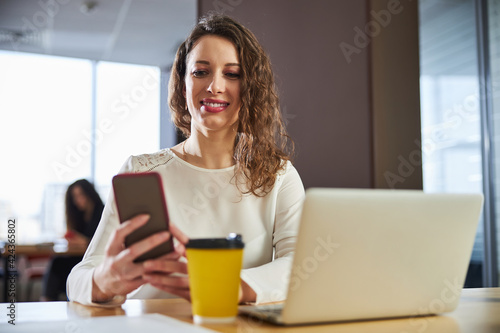 Cheerful young woman using smartphone at work