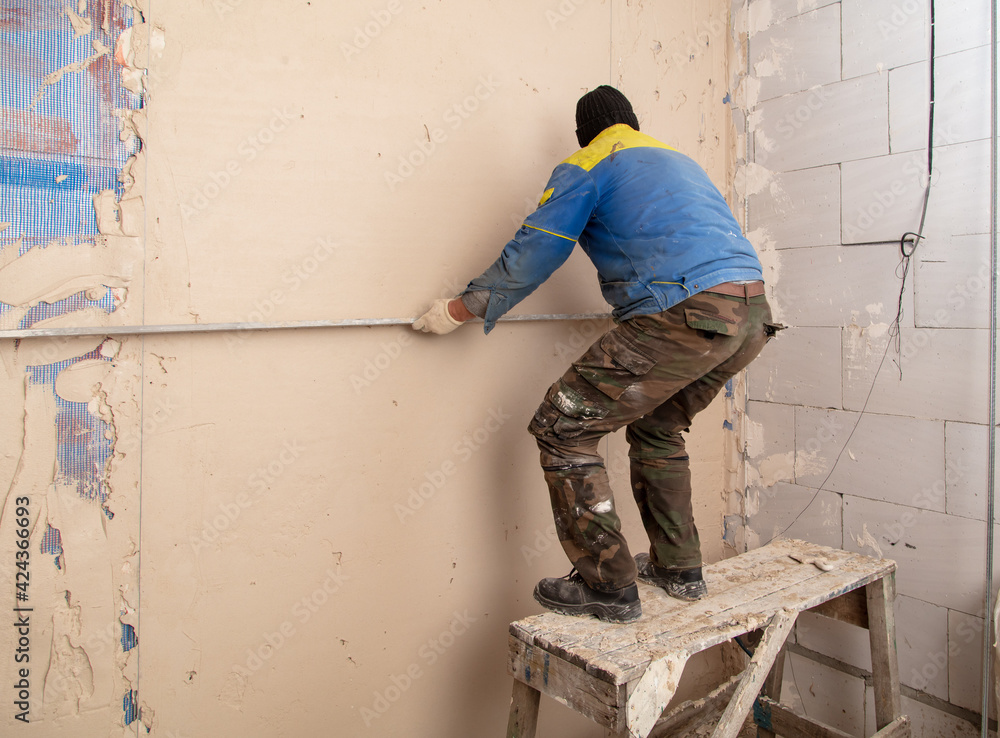 A worker plasters the walls in the room.