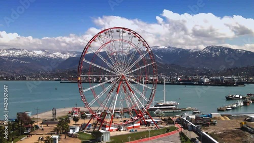 Dolly zoom. Parallax effect. Drone footage ferris wheel on embankment and amazing mountain scenery 