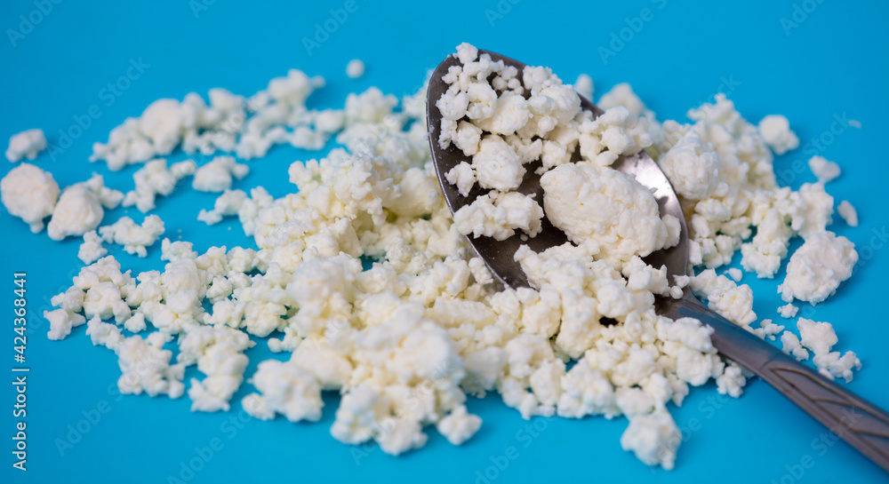 Milk curd in a spoon on a blue background. Milk curd in a spoon on a blue background.