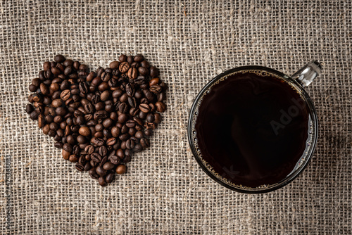 Coffee beans heart and cup of coffee on linen background.