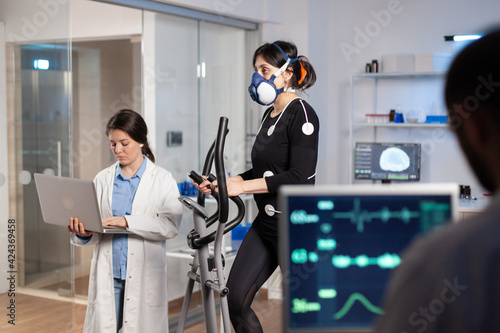 Canvas Print Team of medial researchers monitoring vo2 of woman performance sports wearing mask running
