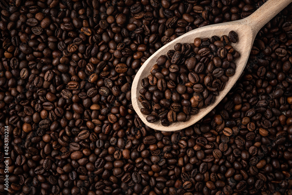 Fototapeta premium Coffee beans with wooden spoon background or texture.