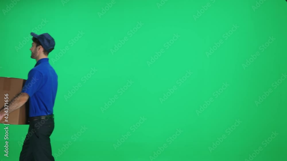 Man courier in uniform walks with a cardboard box in his hands on a green background, delivery service, chromakey template. Man courier in uniform walks with a cardboard box in his hands on a green background, delivery service, chromakey template.