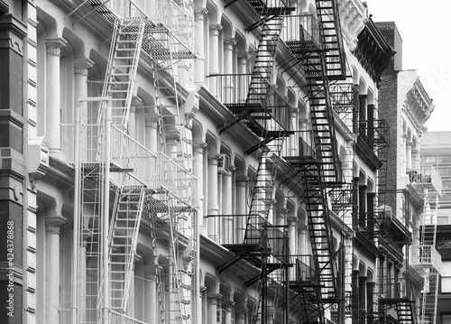 Row of old buildings with iron fire escapes, black and white picture, New York City, USA.