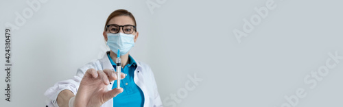 A doctor on a light background holds a syringe with a coronavirus vaccine. defense Pandemic Covid-19