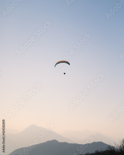Paragliding at sunset over the mountains, Italy