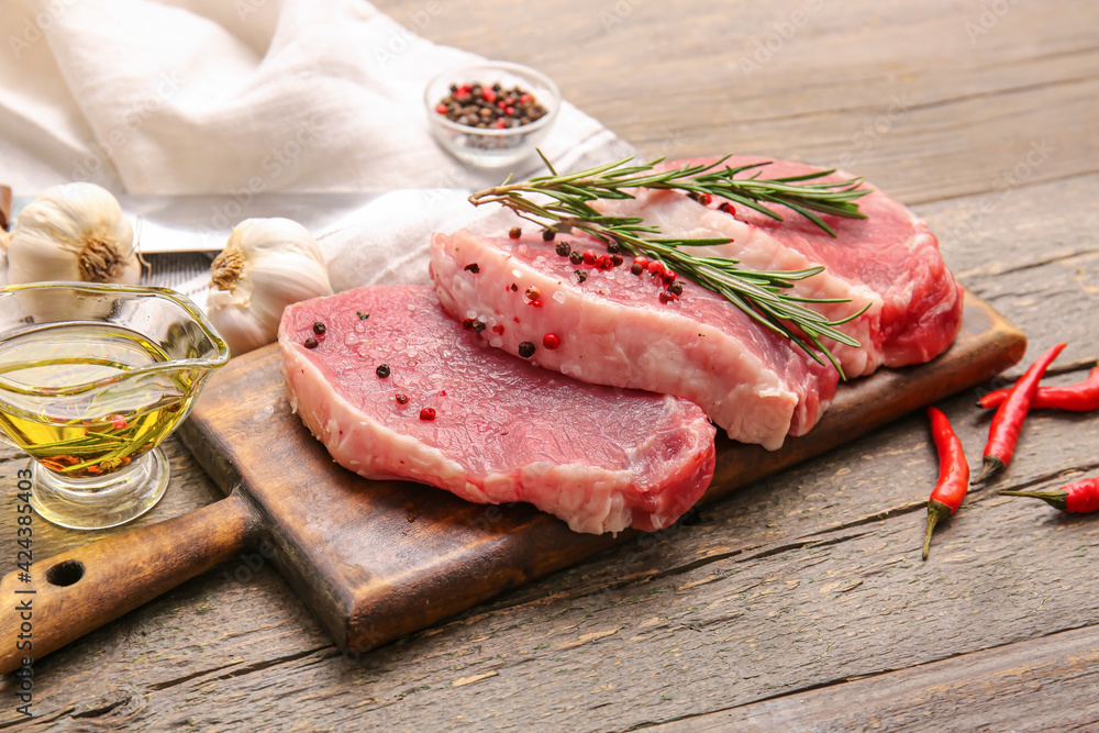 Board with fresh raw meat and spices on wooden background