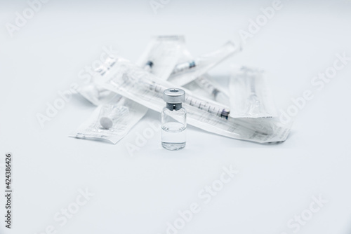 Bottle of  a drug or vaccine against Covid-19 Corona Virus with a group of syringes still packed, isolated on white background.