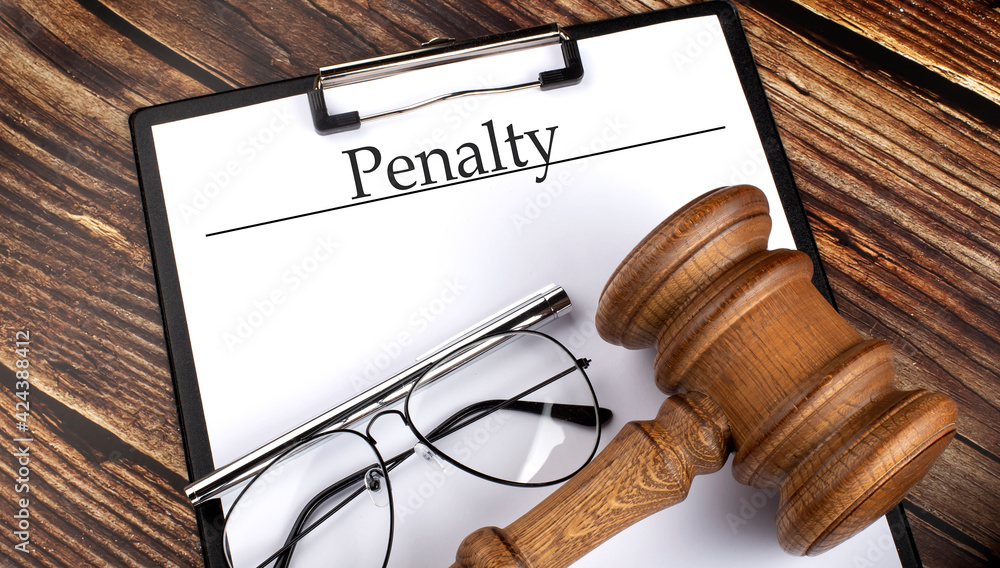 Paper with Penalty with gavel, pen and glasses on the wooden background Paper with Penalty with gavel, pen and glasses on the wooden background