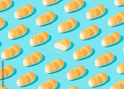 Real life bakery pattern made of fresh homemade cryspy bread on pastel blue background. Sliced pastry. Bright light, sharp shadows.