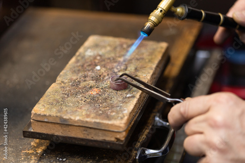 goldsmith jeweler soldering a silver ring on the workbench with a soldering.