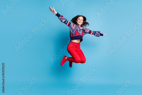 Full length body size view of pretty cheerful girl jumping like airplane having fun isolated over bright blue color background