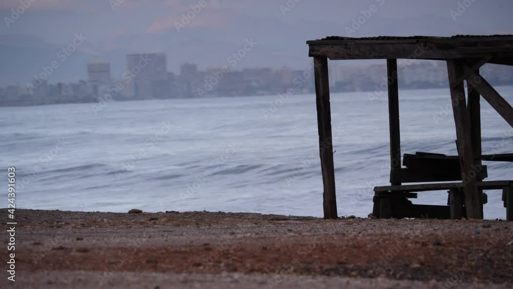 Coastal landscape, empty beach shore with rest place, Alicante city in the distance. Spain, Costa Blanca. Waves moving in slow motion. Coastal landscape, empty beach shore with rest place, Alicante city in the distance. Spain, Costa Blanca. Waves moving in slow motion.