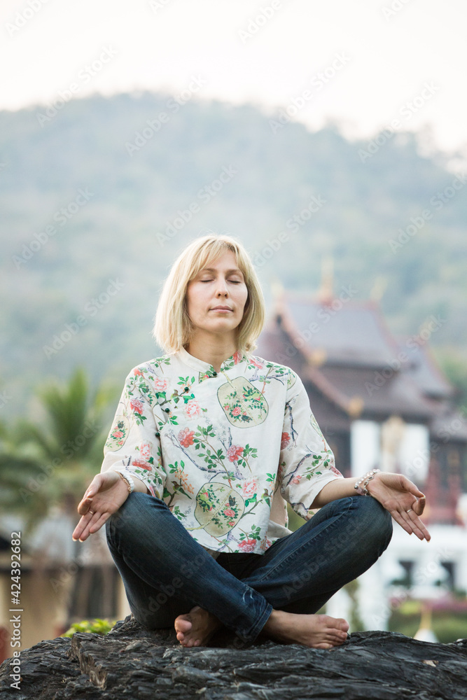 Buddhist blonde girl in the garden trying to meditate
