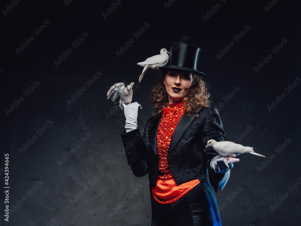 Serious female magician with white pigeons and top hat in dark background Serious female magician with white pigeons and top hat in dark background