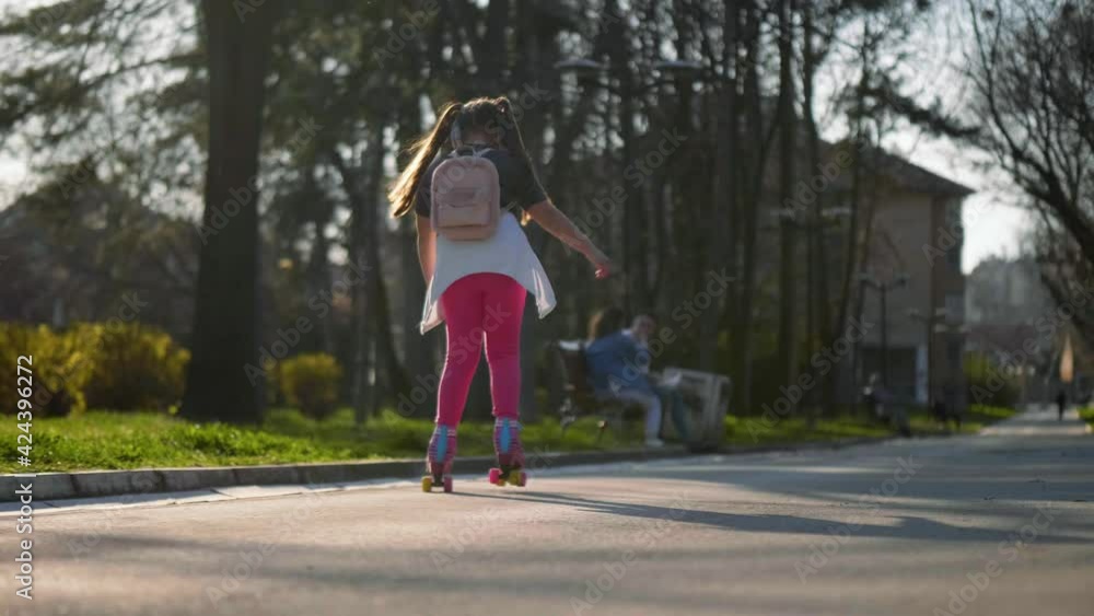 Little girl with a backpack travels to school on roller skates. Slow motion. Back to school Little girl with a backpack travels to school on roller skates. Slow motion. Back to school