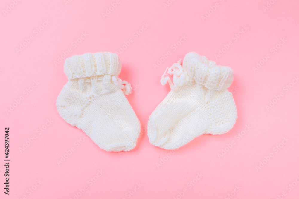 knitted baby booties on pastel pink background. knitted baby booties on pastel pink background.