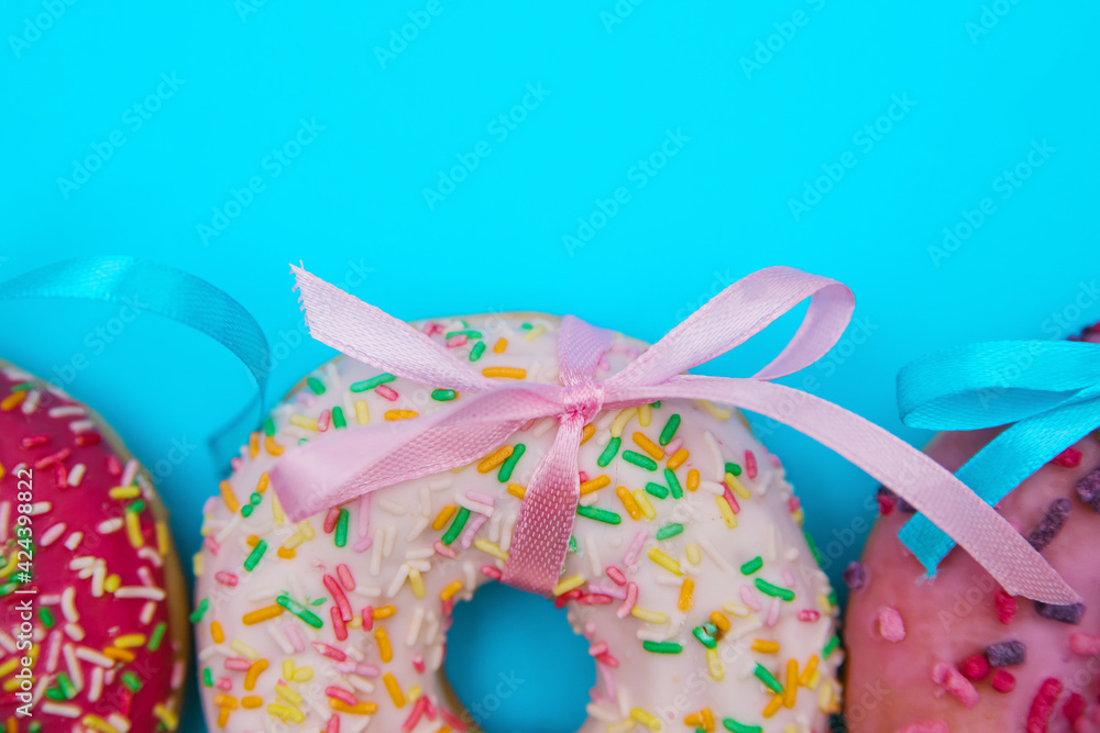 Sweet donuts of different colors are arranged in a row on a blue background. Sweet donuts of different colors are arranged in a row on a blue background.