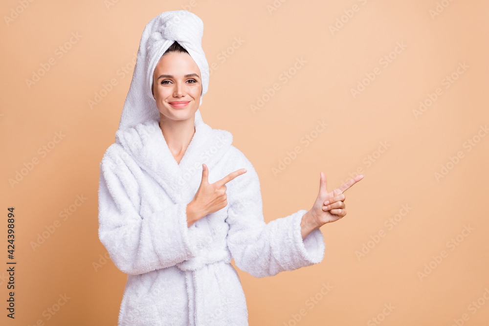 Portrait of pretty cheery girl wear bathrobe demonstrating copy space idea solution isolated over beige pastel color background Portrait of pretty cheery girl wear bathrobe demonstrating copy space idea solution isolated over beige pastel color background