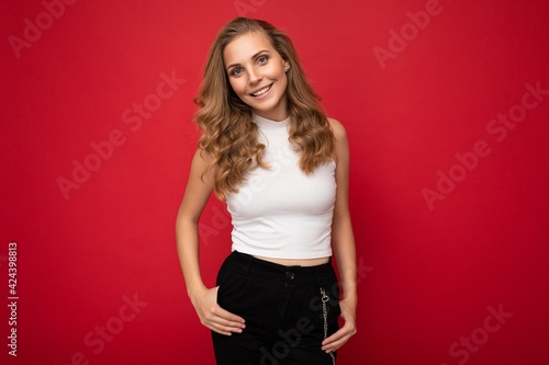 Photo of young charming fascinating attractive happy smiling delightful blonde woman with sincere emotions wearing stylish clothes isolated over red background with copy space © Ivan Traimak