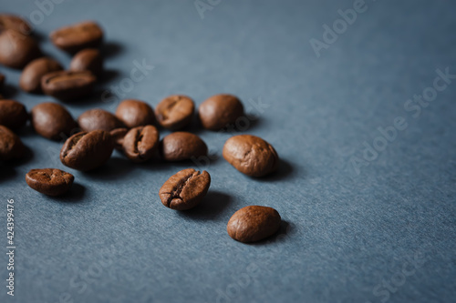 Fototapeta Naklejka Na Ścianę i Meble -  Coffee grain blue background top view. Textured background for the design. Brown roasted macro beans scattered on the table in natural sunlight. Full frame, copy space. Espresso beans, mock-up