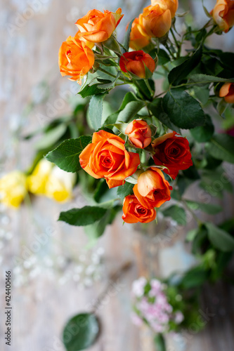 Fresh roses bouquet in orange color on wooden table. Selective focus. Floral background.